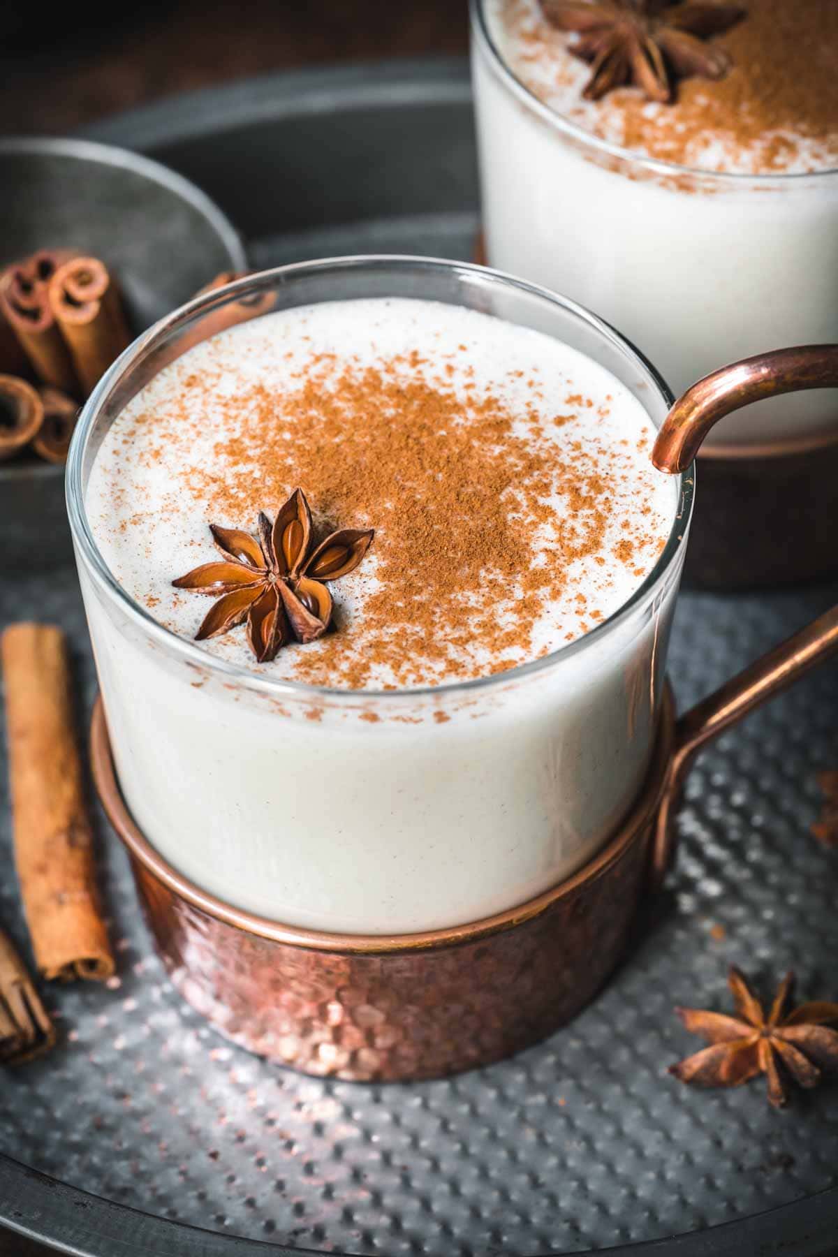 Close up of vegan eggnog in a mug with cinnamon on top and star anise.