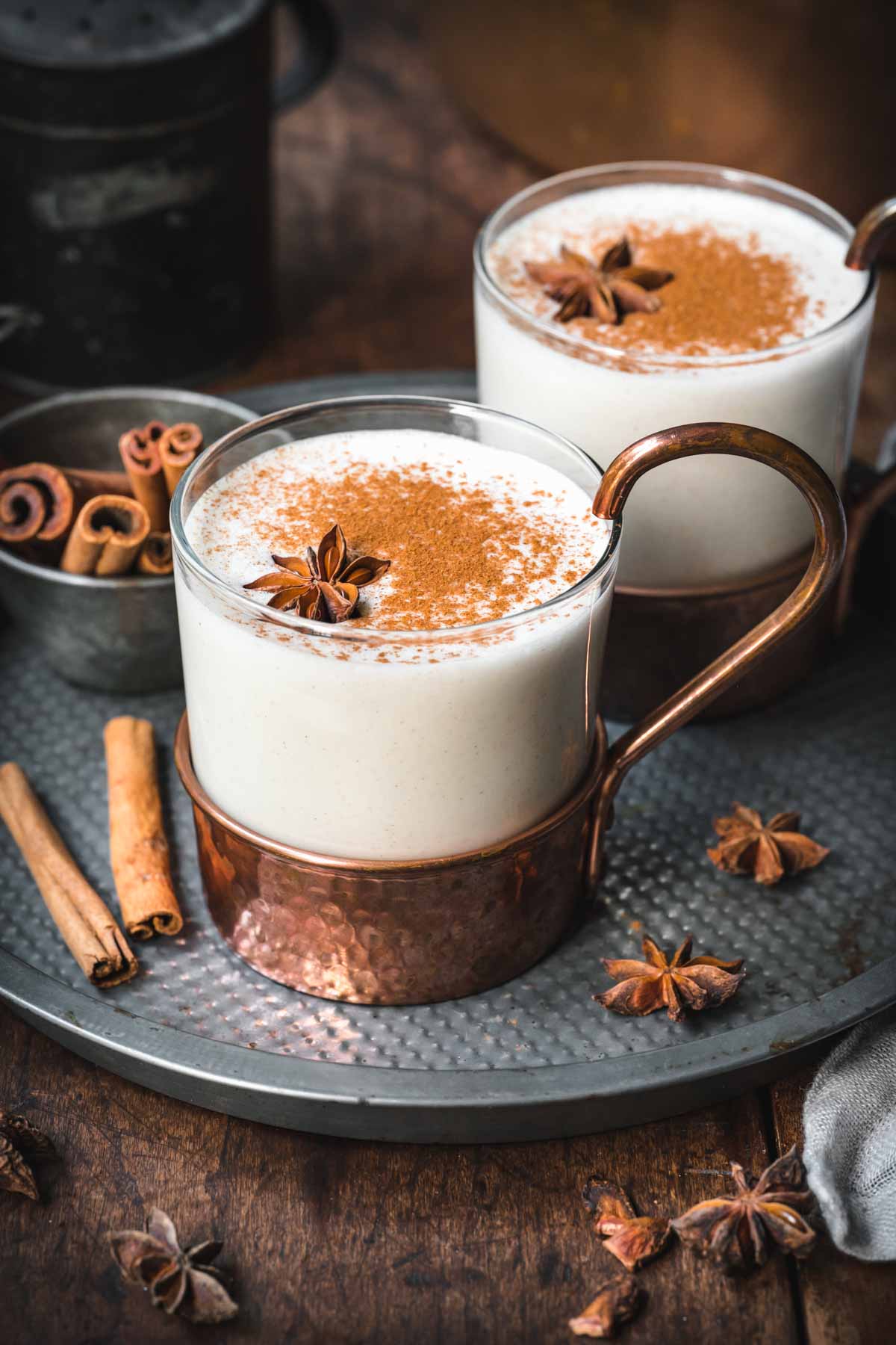 Close up of vegan eggnog in a mug with cinnamon on top and star anise.