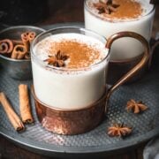 Close up shot of vegan eggnog in a transparent mug with cinnamon and anise.