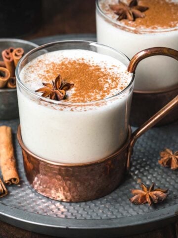 Close up shot of vegan eggnog in a transparent mug with cinnamon and anise.