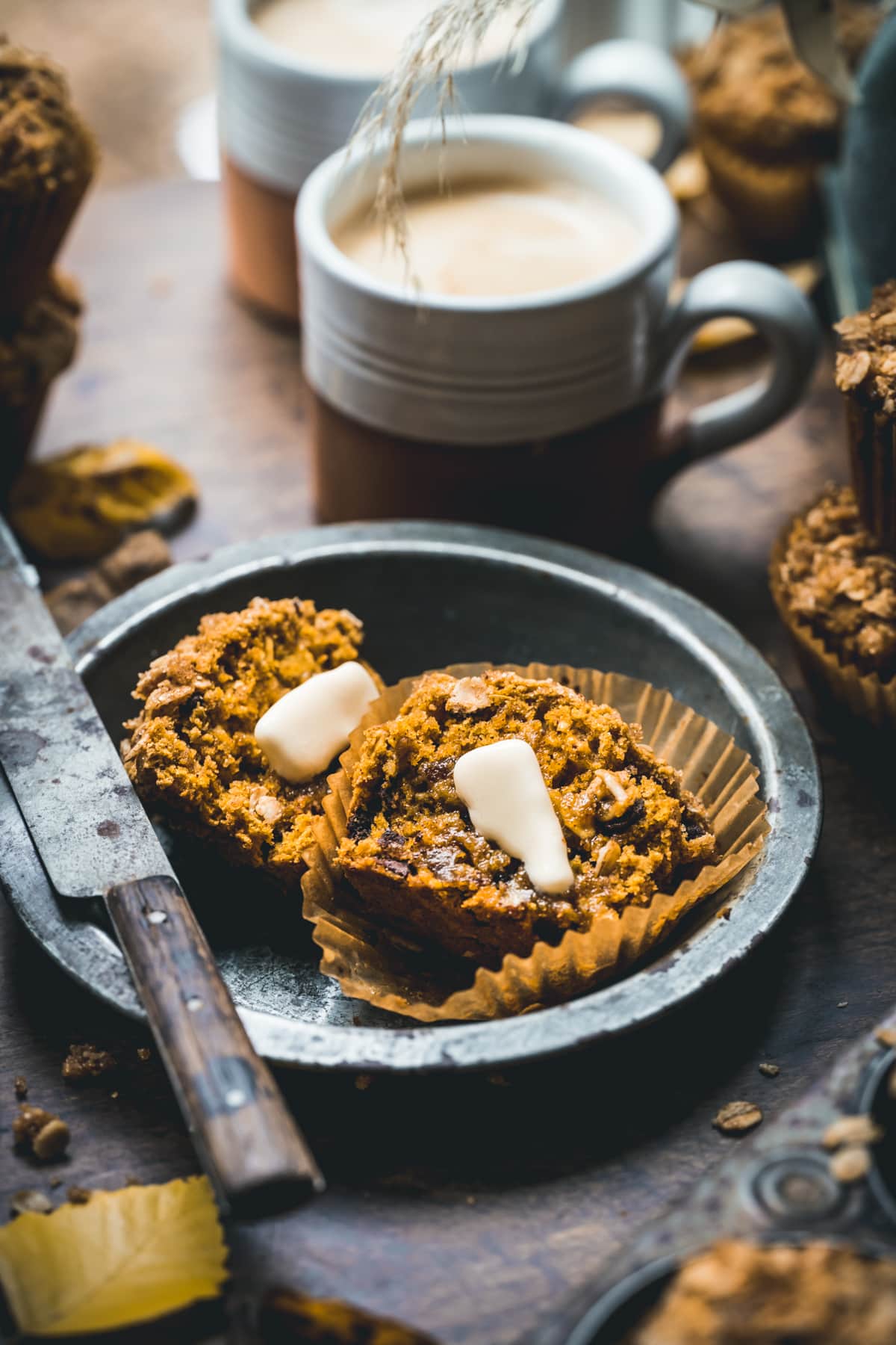 Close up shot of pumpkin muffin sliced in half with a pat of butter in the middle.