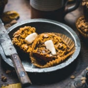 Close up of a pumpkin muffin sliced in half with a pat of butter.