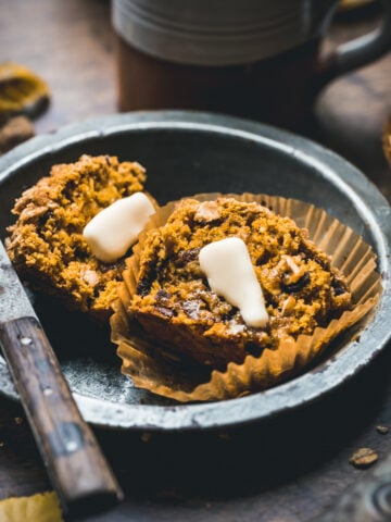 Close up of a pumpkin muffin sliced in half with a pat of butter.