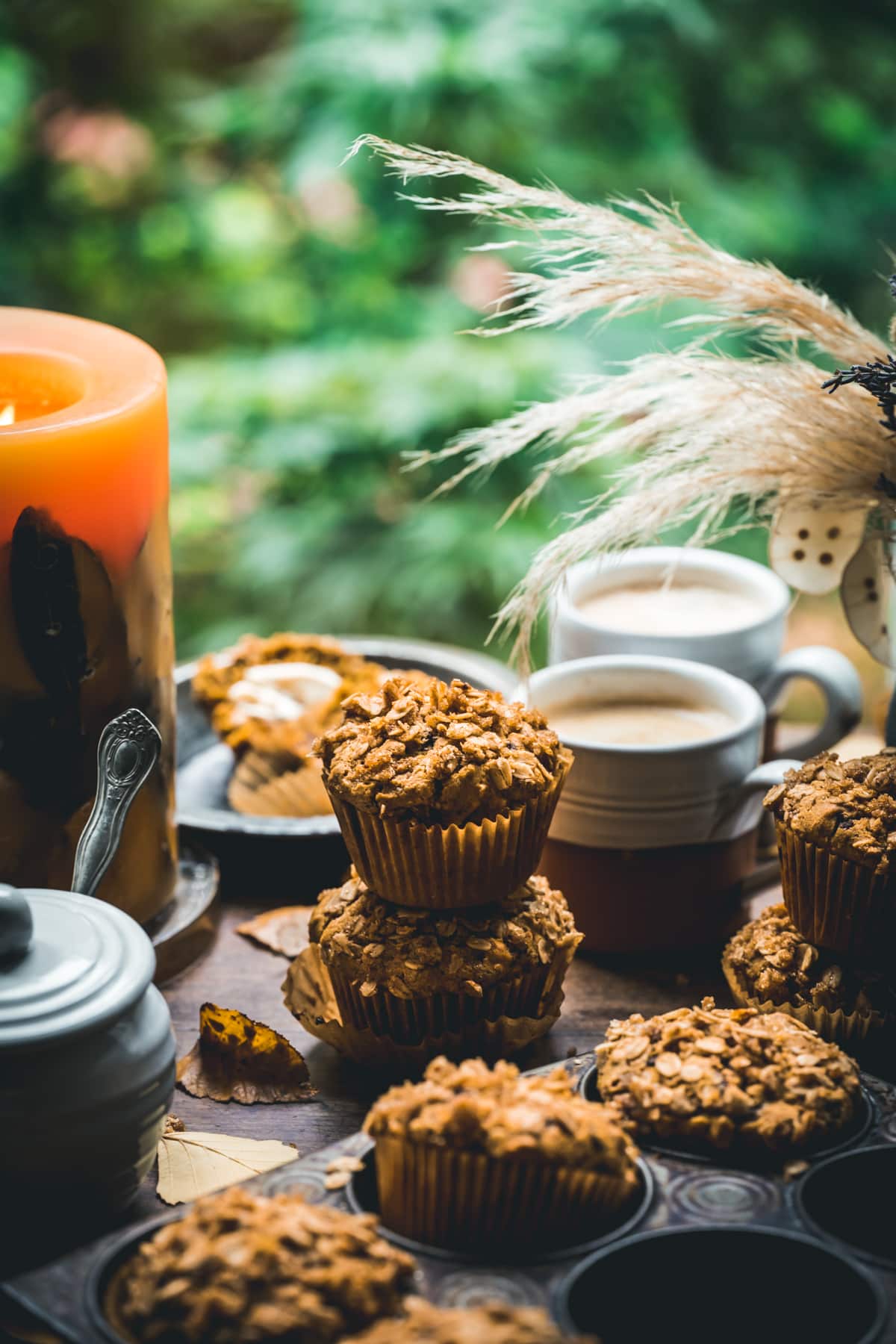 Stack of two vegan pumpkin muffins on wood table in front of window. 