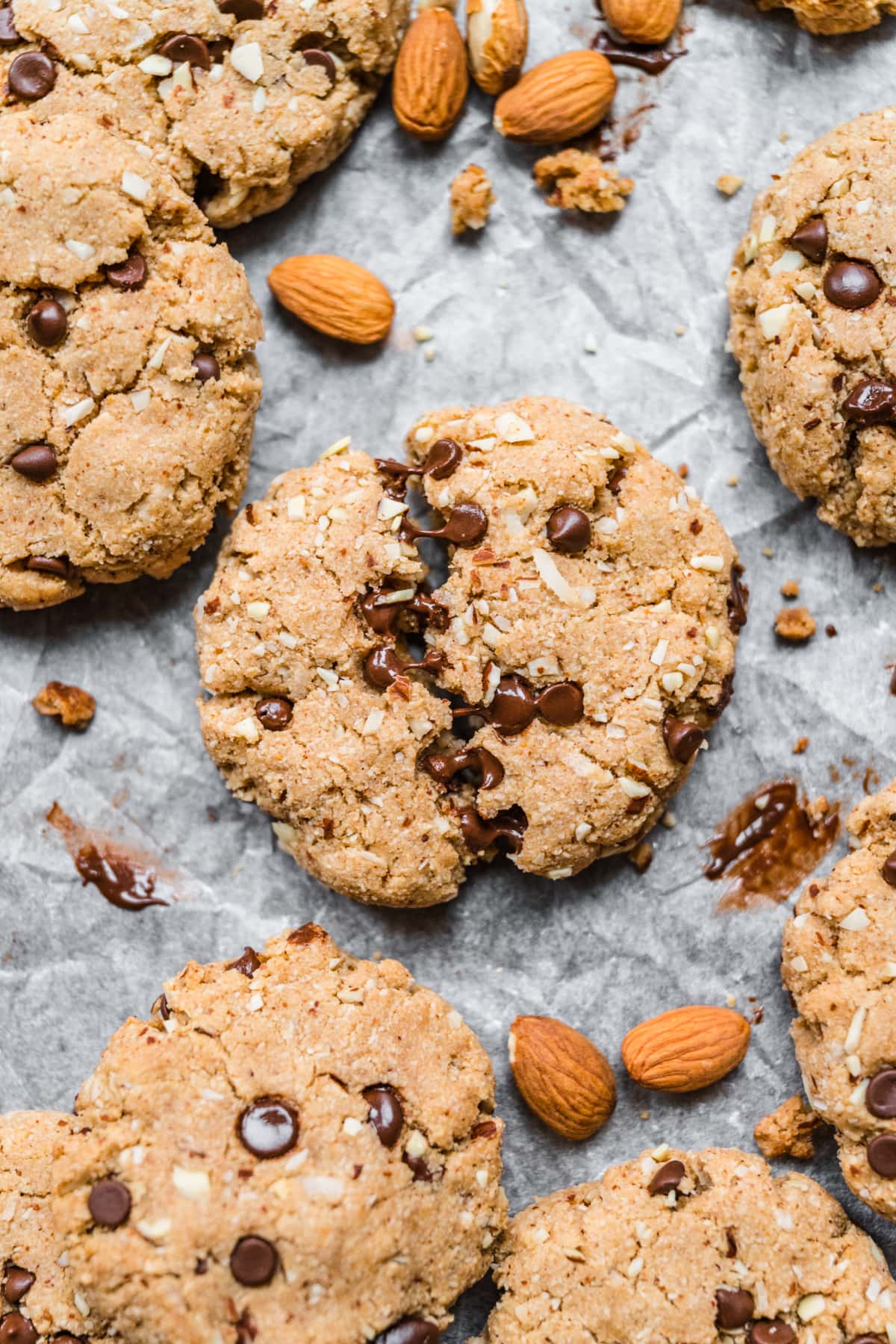 close up view of chocolate chip almond flour cookie broken in half with melted chocolate showing. 