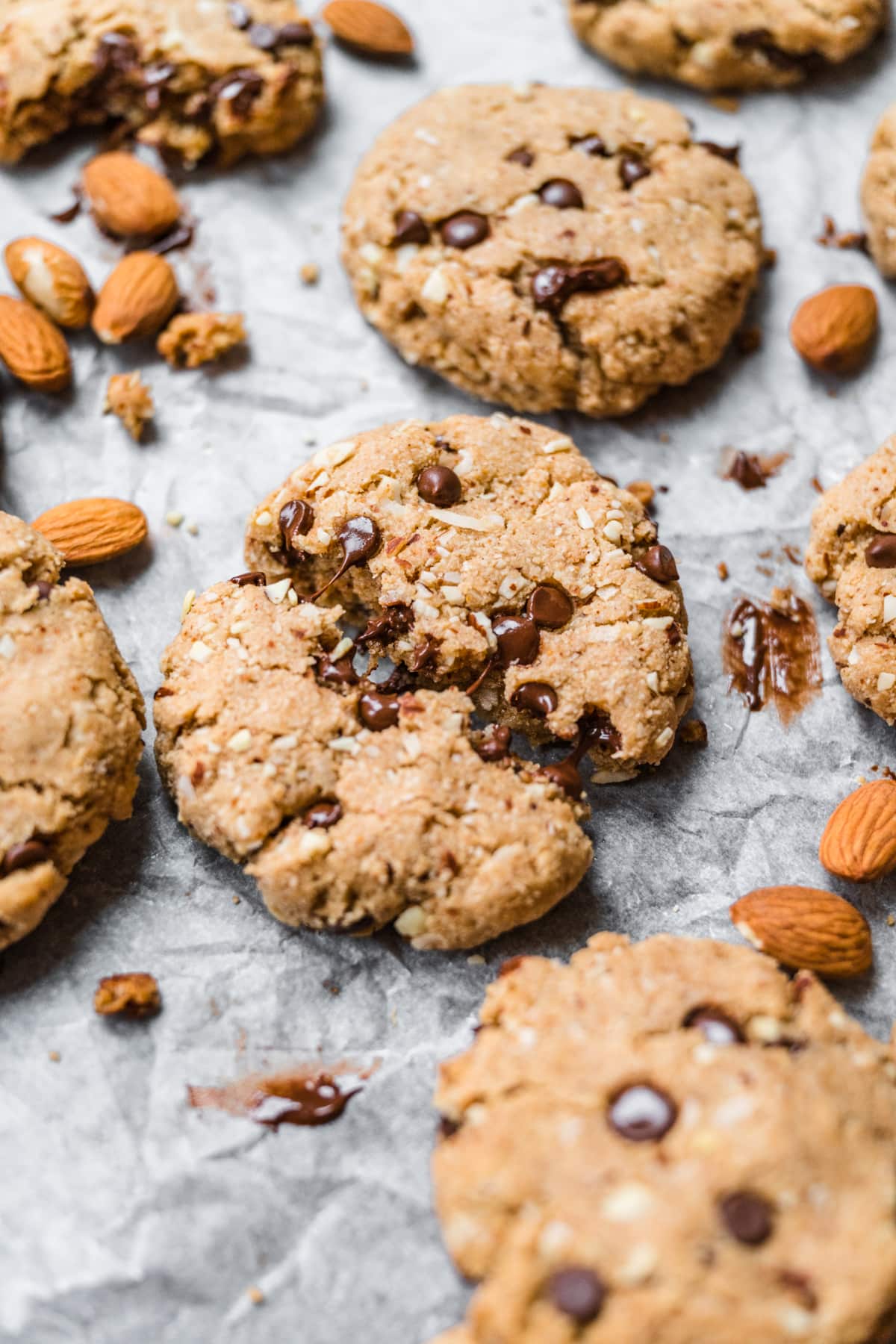 close up view of chocolate chip almond flour cookie broken in half with melted chocolate showing. 