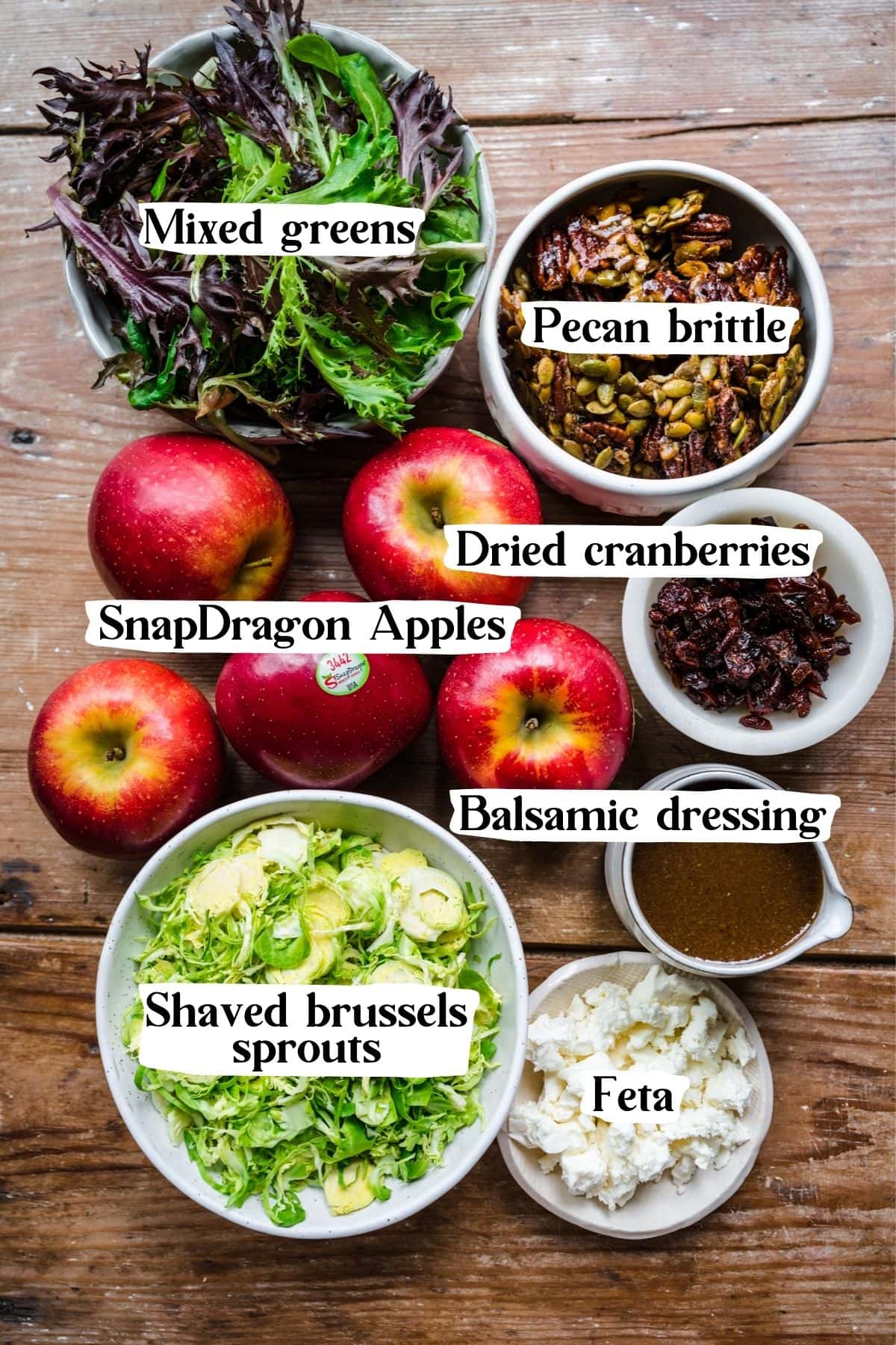 Overhead view of salad ingredients, including apples, greens, and balsamic dressing.