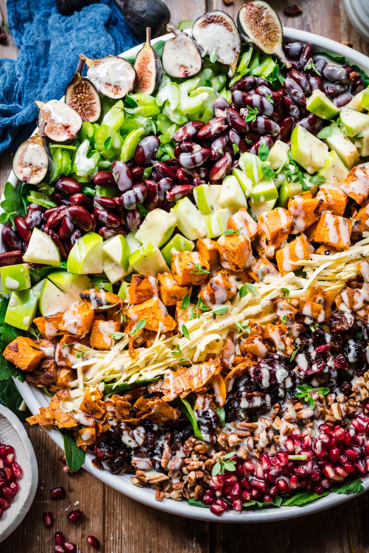 close up overhead view of vegan fall cobb salad on a large salad plate on wood table. 