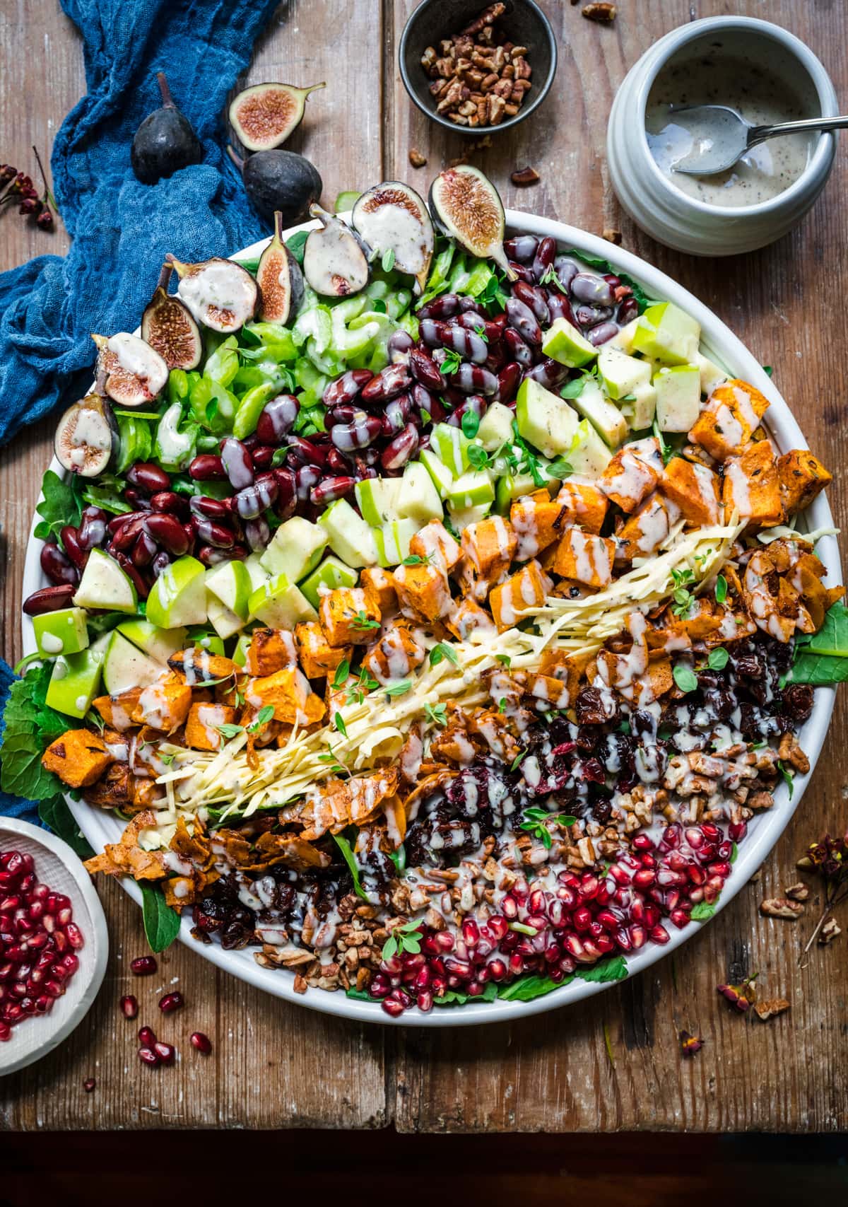 overhead view of vegan fall cobb salad on a large salad plate on wood table. 