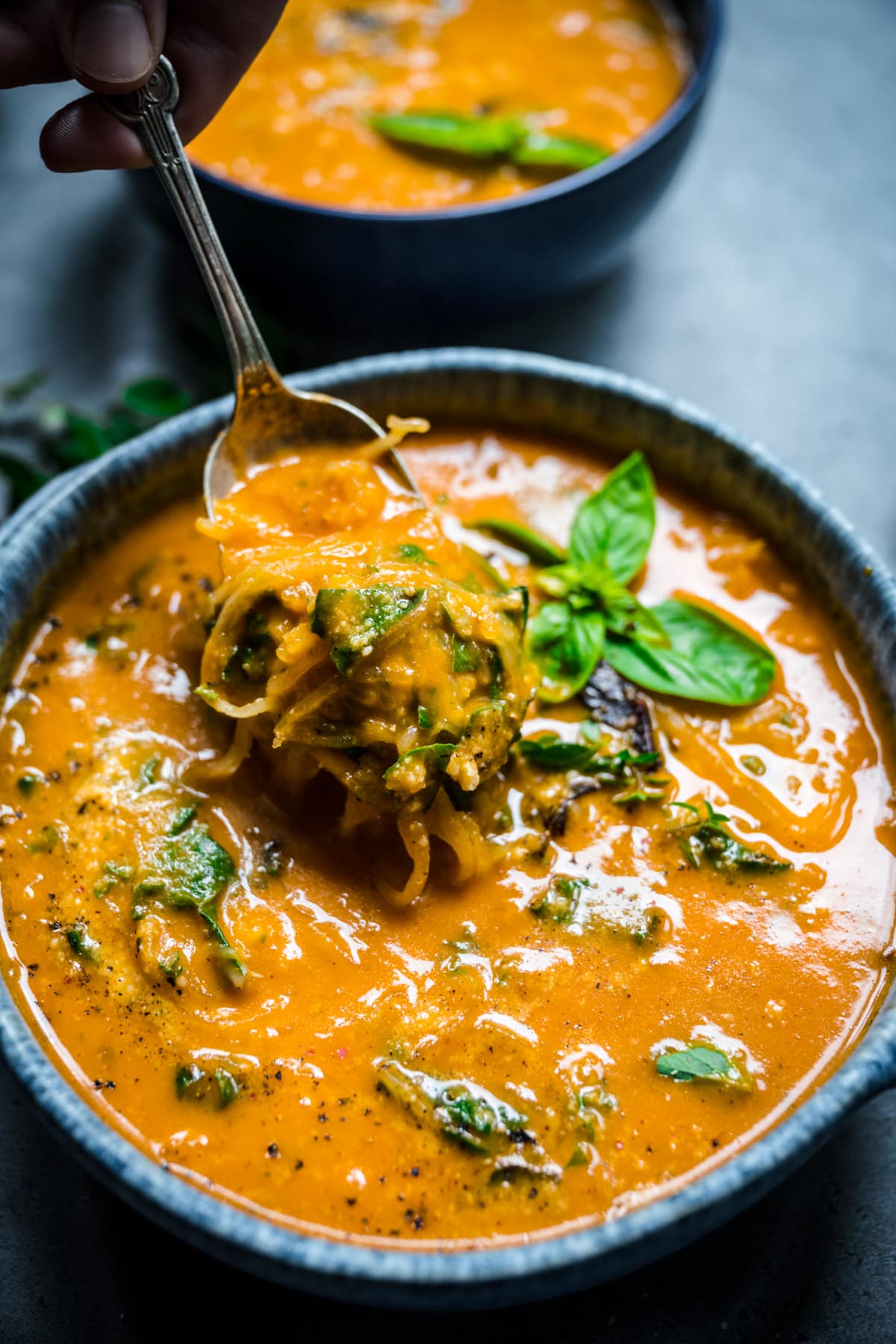 Close up view of spaghetti squash soup with a spoonful of spaghetti squash.