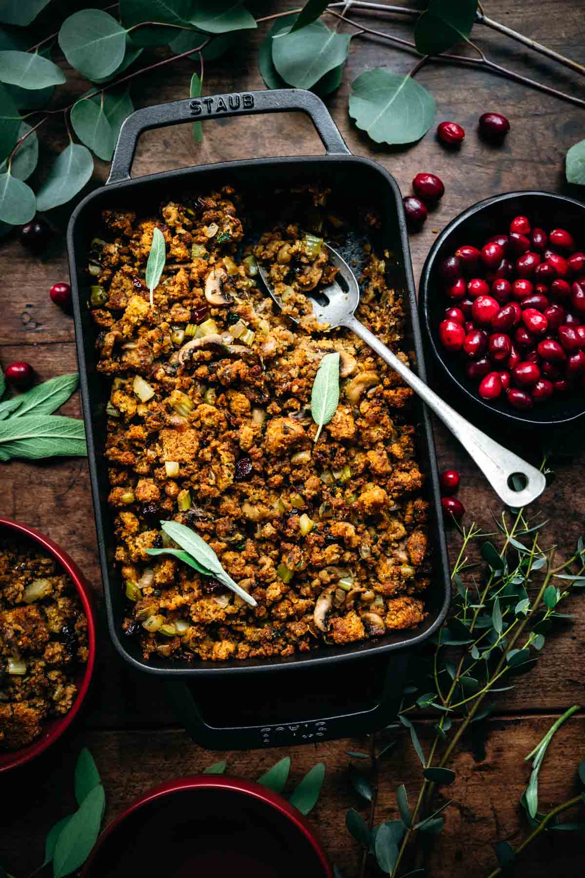 Overhead view of cornbread stuffing in a pan with a serving spoon.