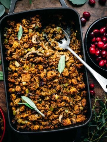 Overhead view of cornbread stuffing in a pan with a serving spoon.