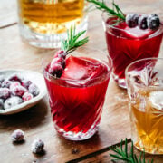 Front view of a christmas old fashioned garnished with cranberry and rosemary.