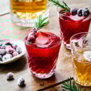Front view of a christmas old fashioned garnished with cranberry and rosemary.