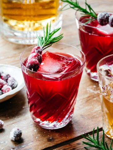 Front view of a christmas old fashioned garnished with cranberry and rosemary.