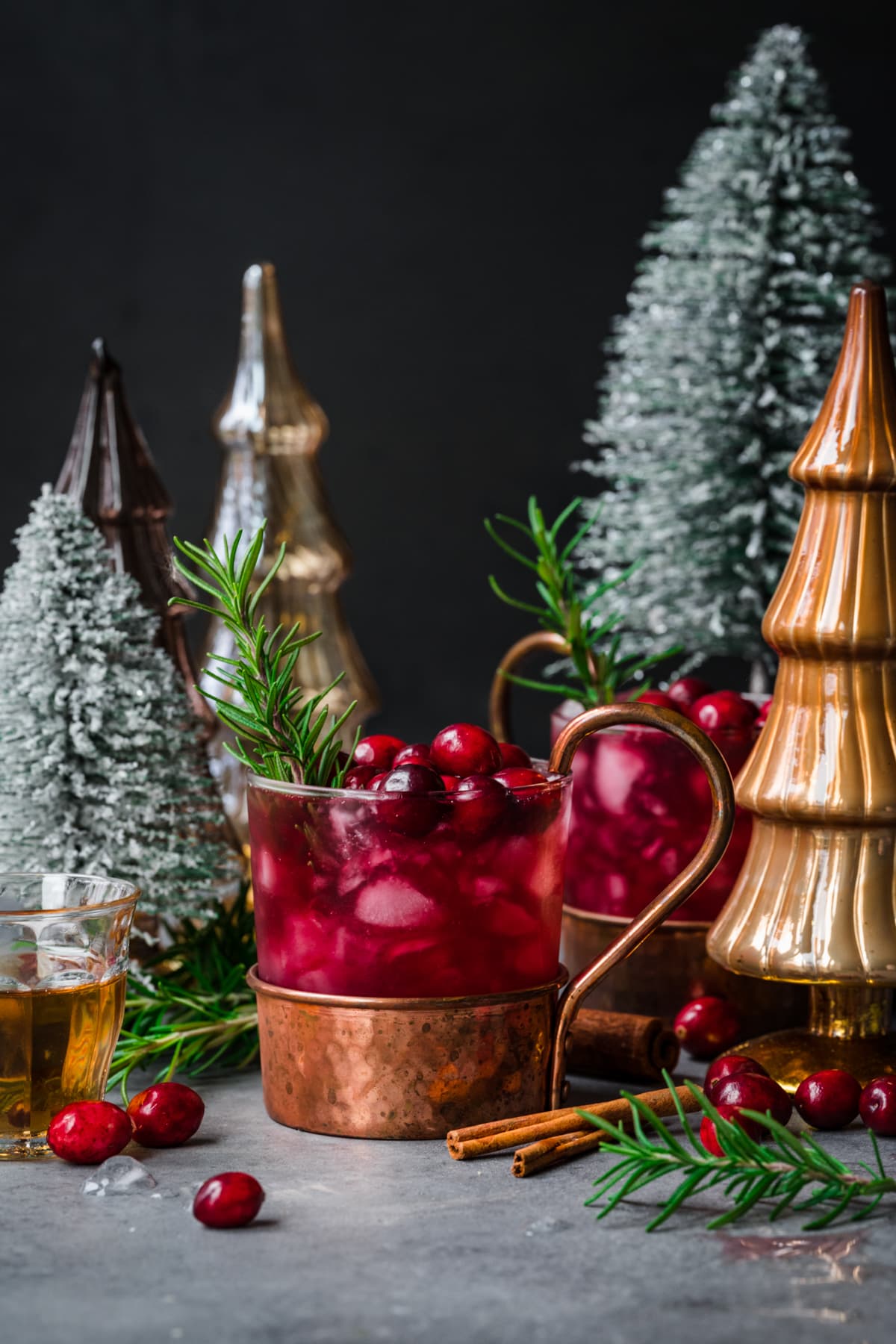 Front view of a cranberry moscow mule cocktail with a sprig of rosemary and cranberry.