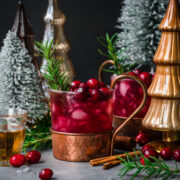 Front view of cranberry moscow mule garnished with cranberries and rosemary.