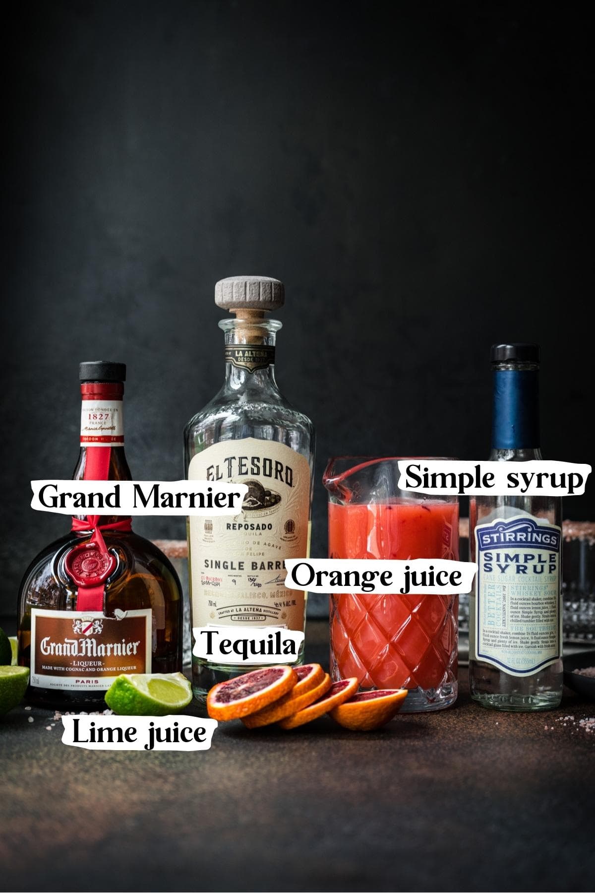Front view of grand marnier ingredients, including Grand Marnier, lime juice, blood orange juice, and simple syrup.