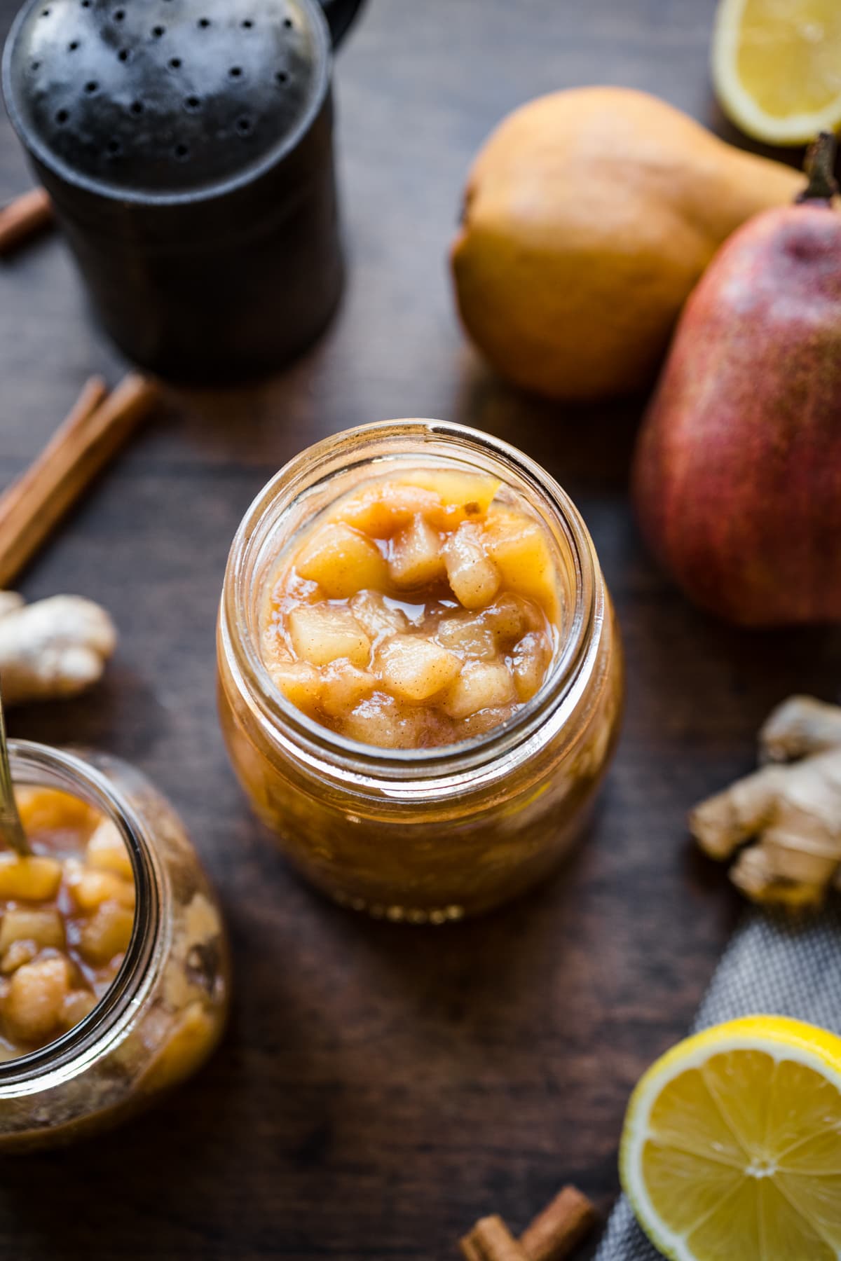 close up view of homemade pear compote in a glass jar on wood table. 