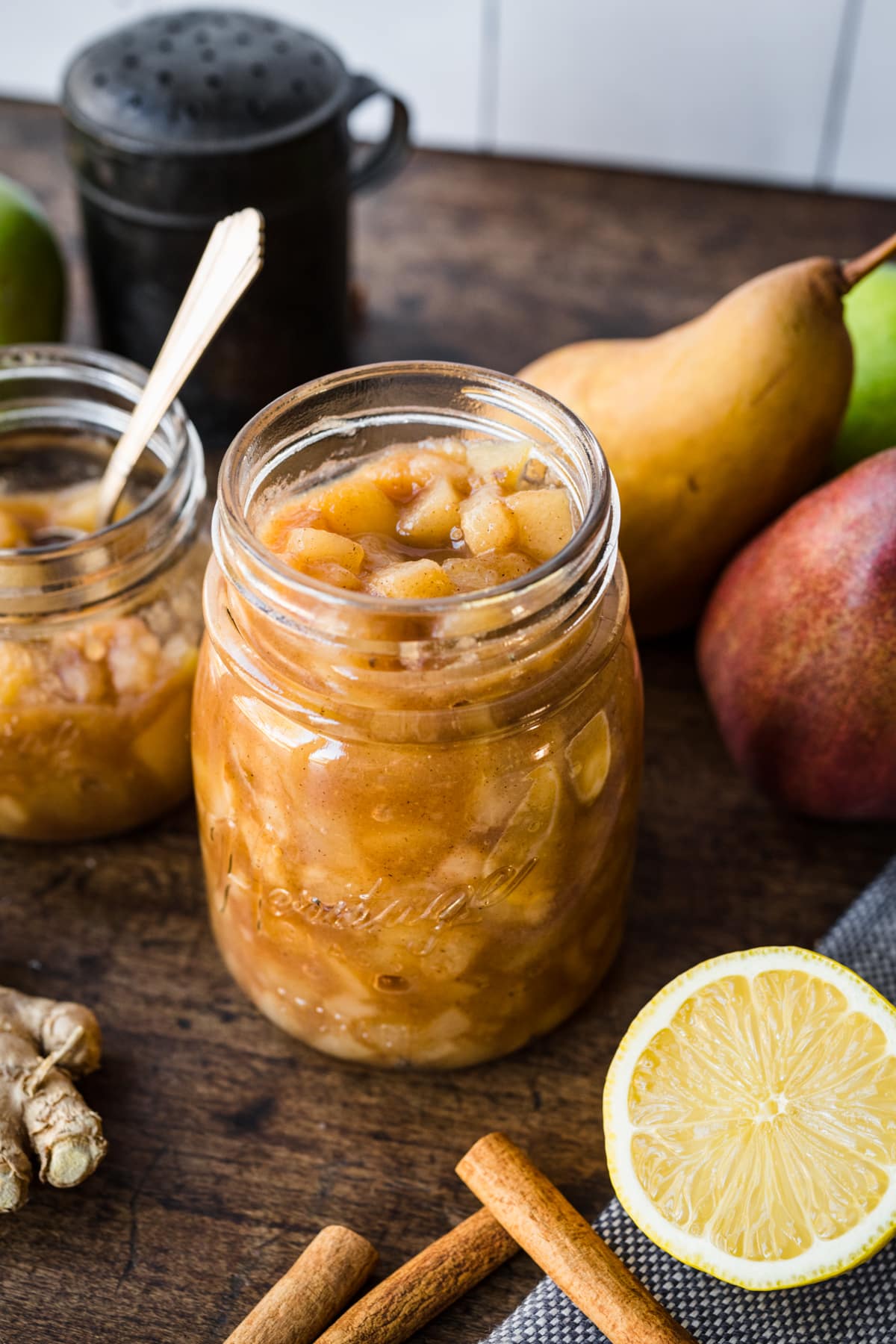 close up view of homemade pear compote in a glass jar on wood table.