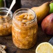 close up view of homemade pear compote in a glass jar on wood table.