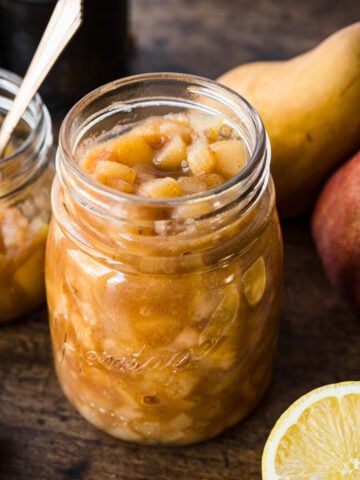 close up view of homemade pear compote in a glass jar on wood table.