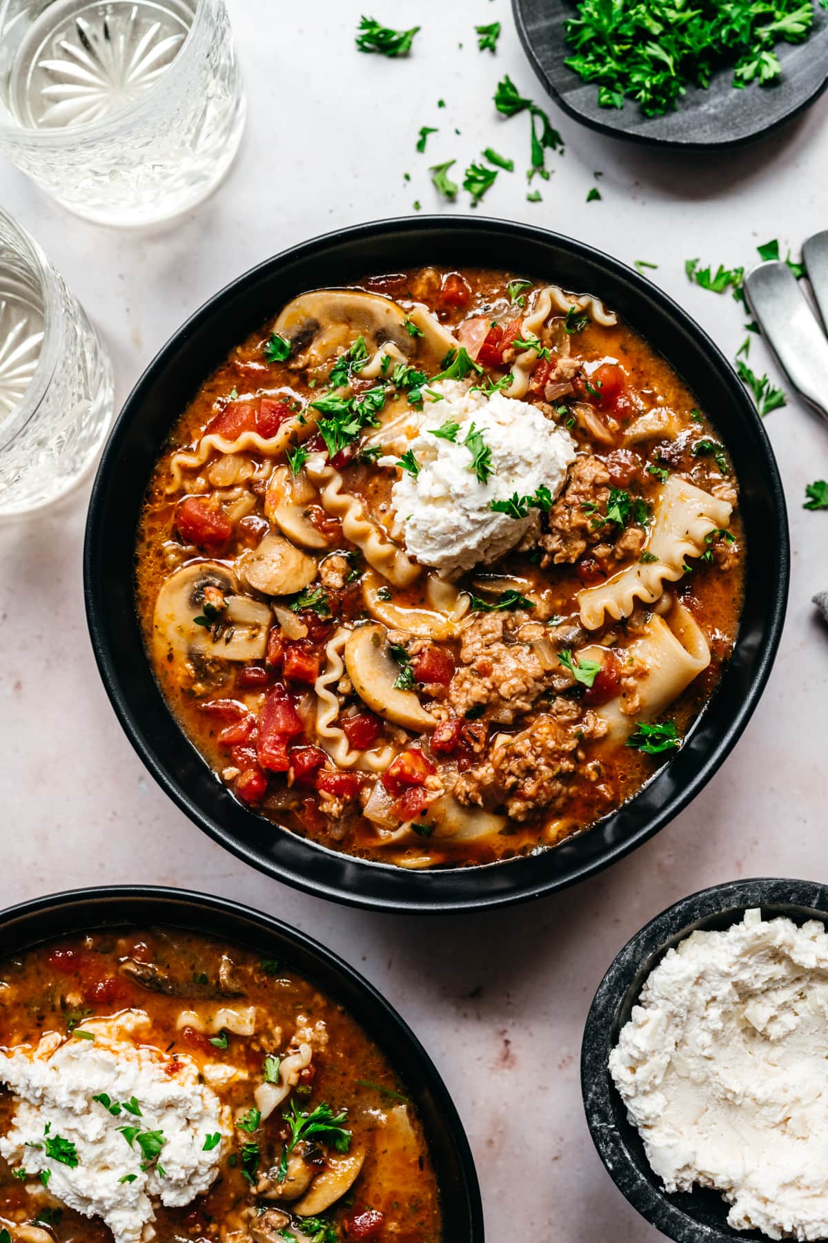 Overhead view of vegan lasagna soup garnished with vegan cheese and herbs.