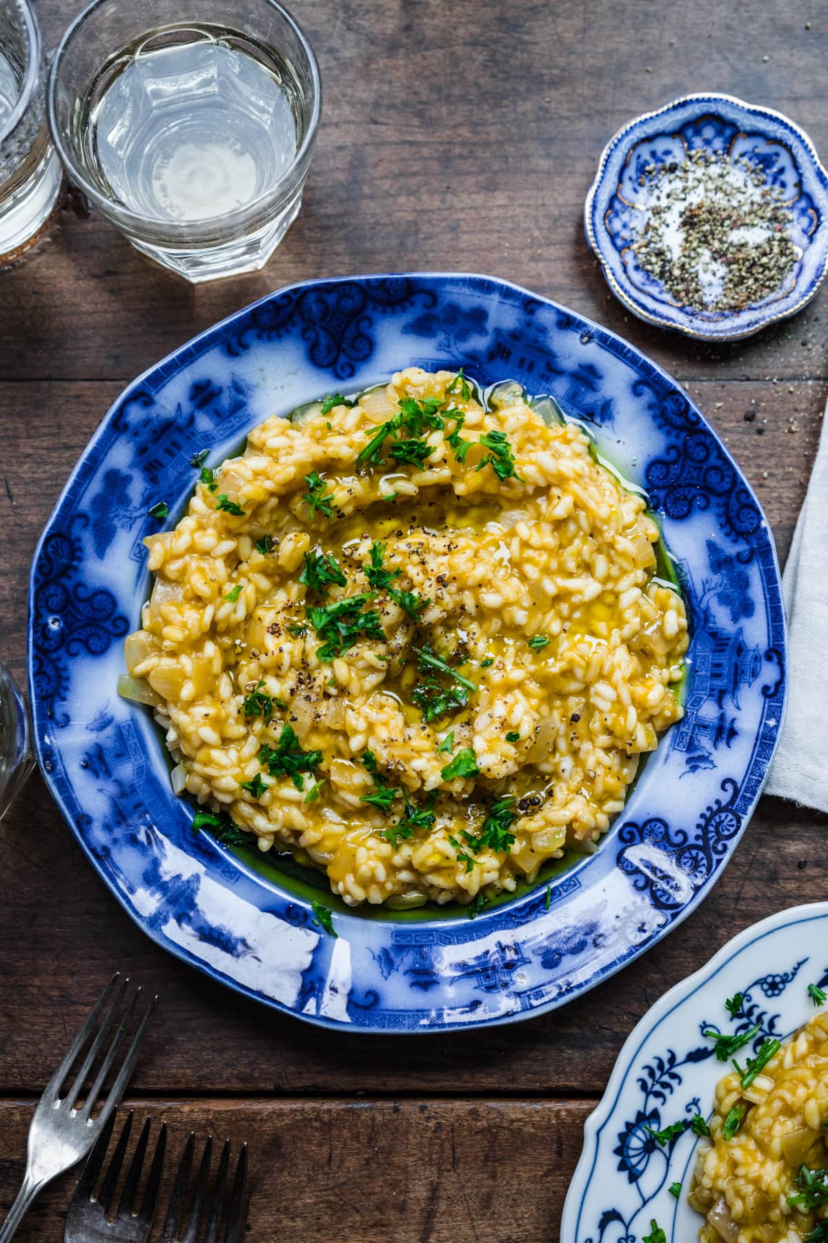 Overhead view of vegan risotto in a blue bowl garnished with herbs.