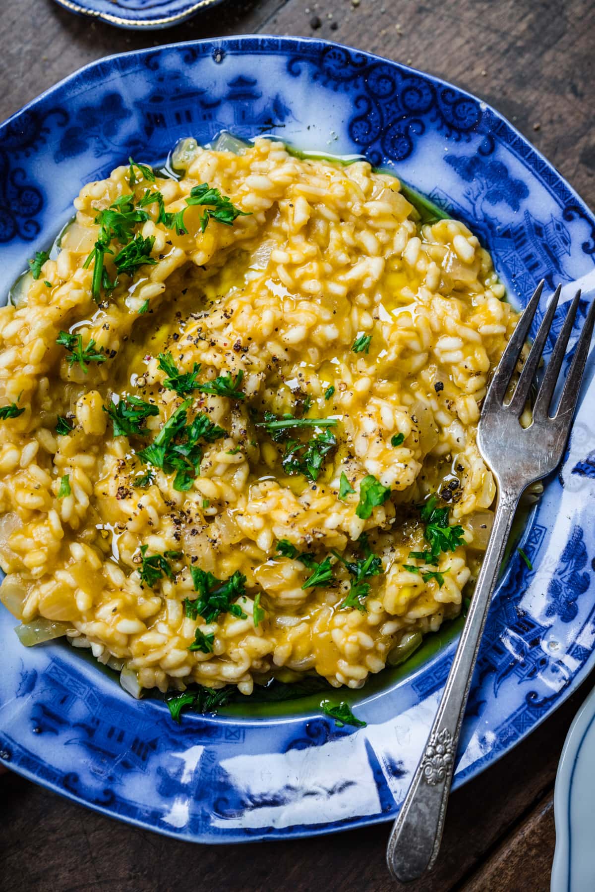 Overhead view of vegan risotto in a blue bowl garnished with herbs.