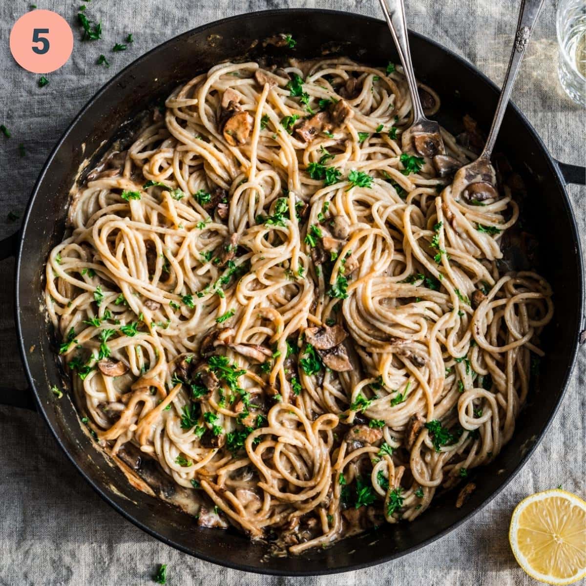 overhead view of vegan carbonara pasta in a large skillet with parsley. 