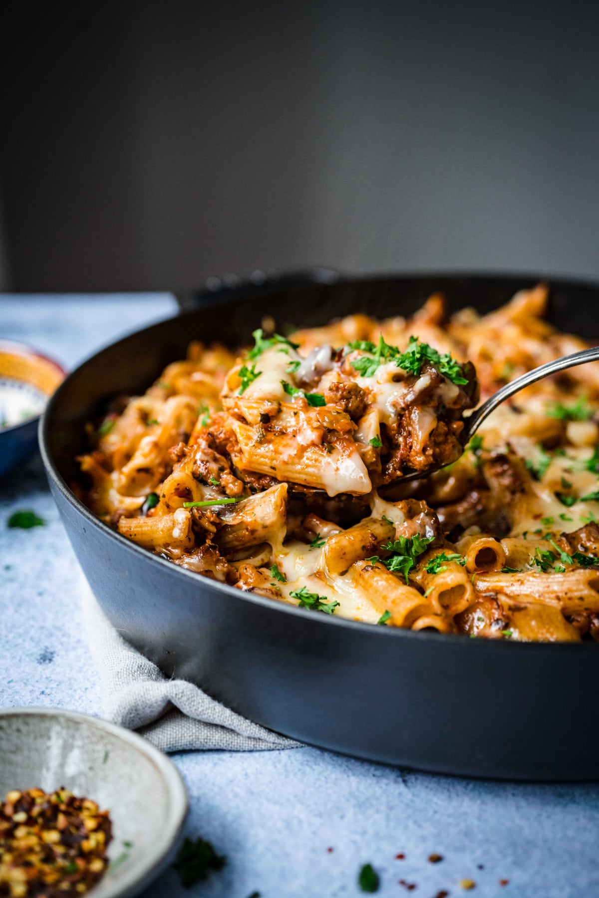 Front view of a fork taking a piece out of pasta al forno in a pan.