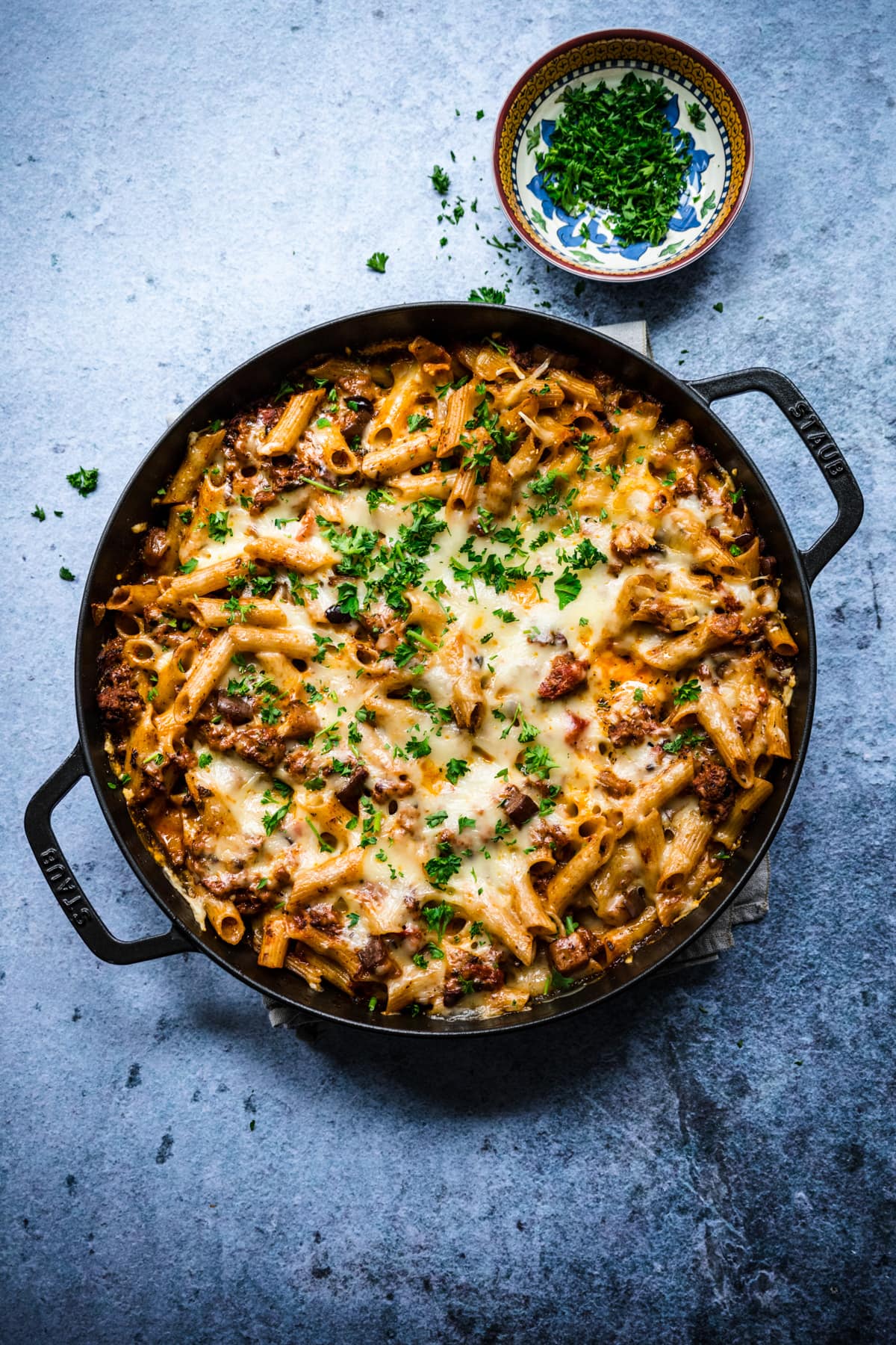 Overhead view of pasta al forno in a cast iron pan garnished with fresh parsley.