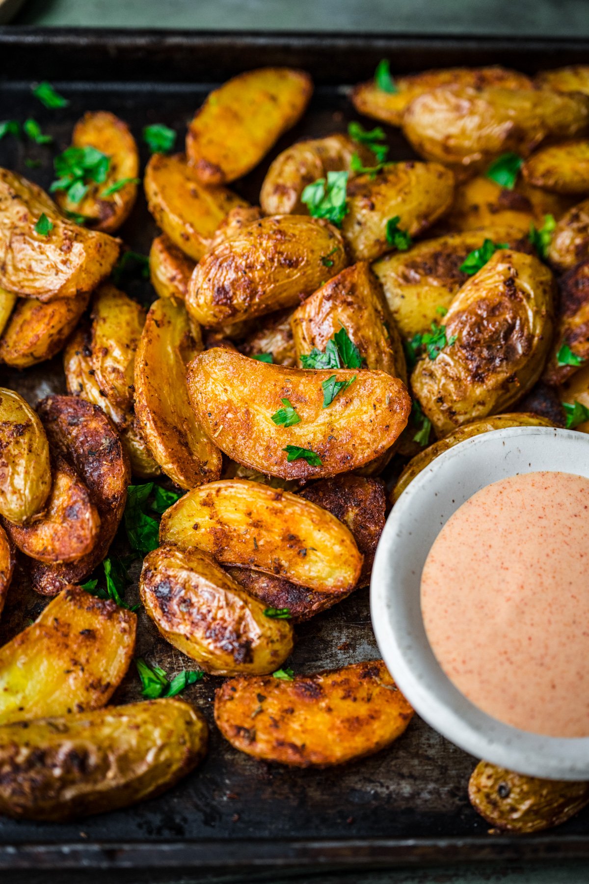 Front view of cajun potatoes alongside a small cup of dip.