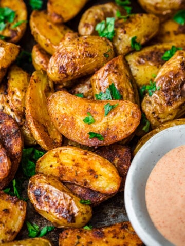 Close up of cajun potatoes with dip on the side.