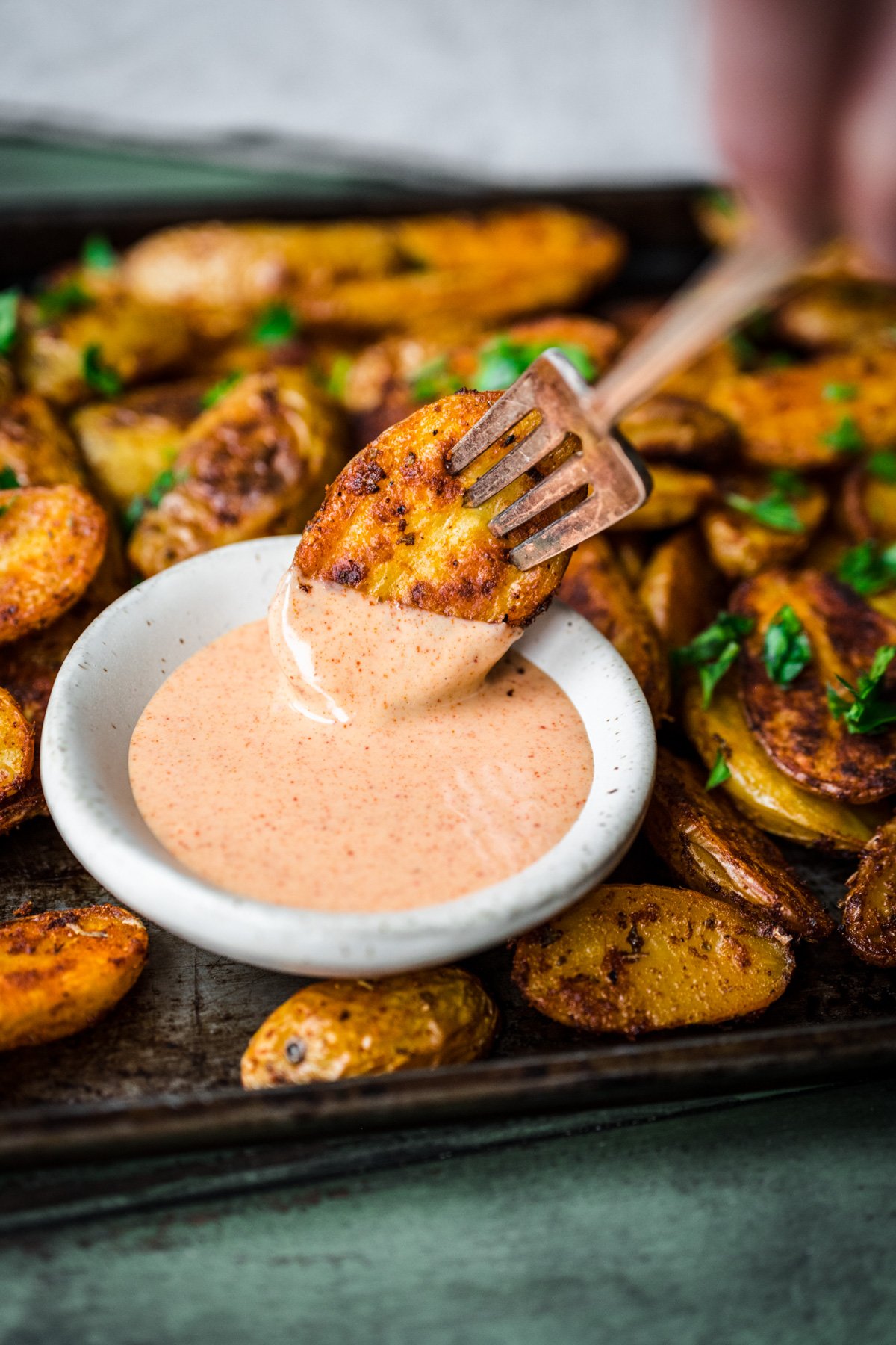 Front view of cajun potato being dipped in sauce.