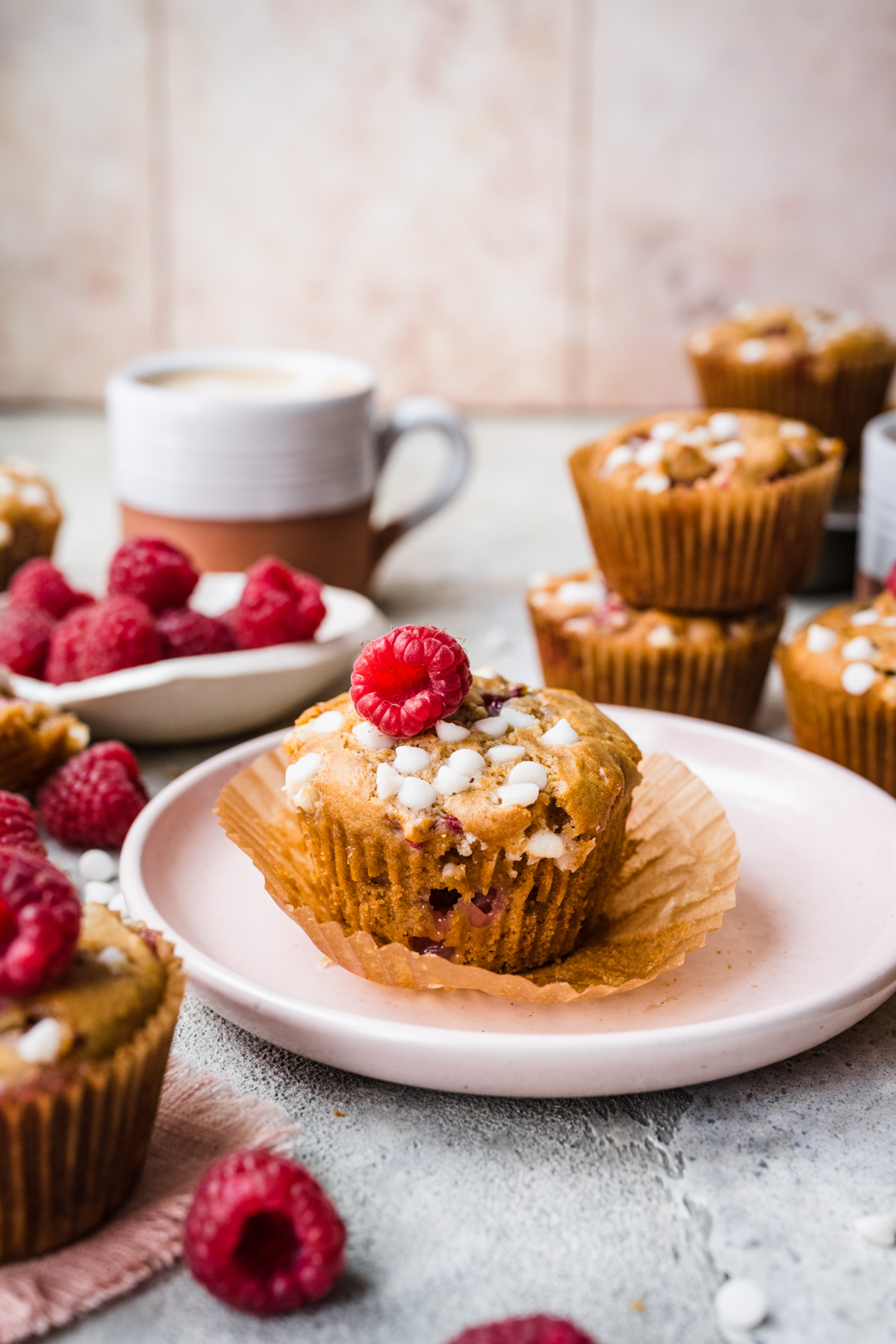 Front view of raspberry white chocolate muffin on a pink plate.