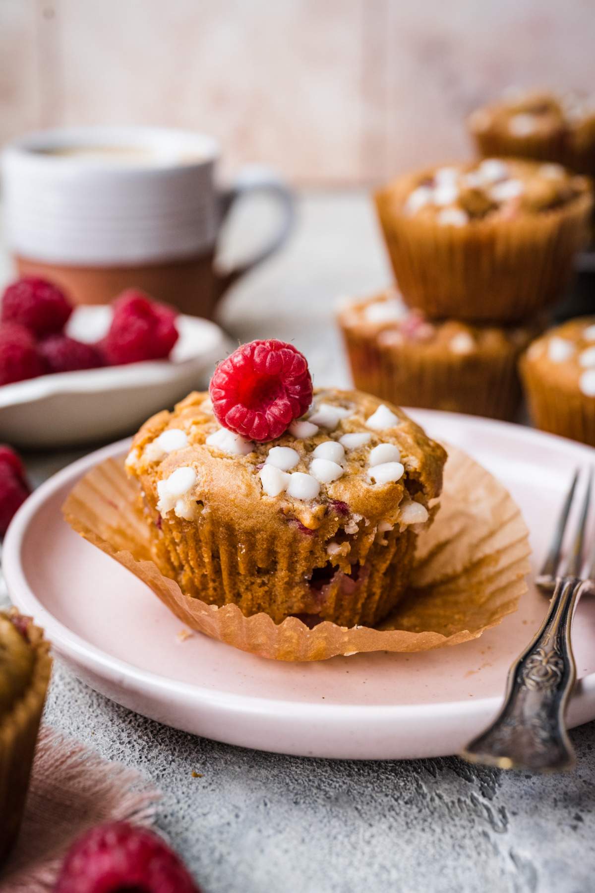 Front view of raspberry white chocolate muffin on a plate.