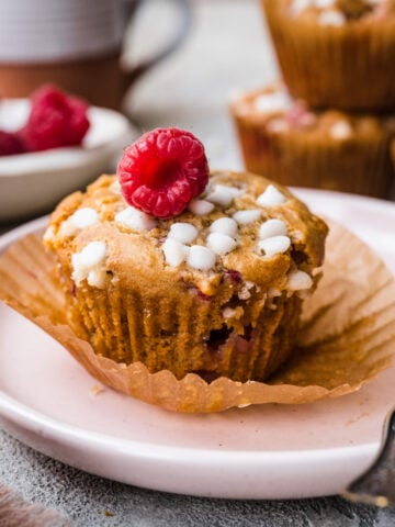 Front view of raspberry white chocolate muffin on a plate.