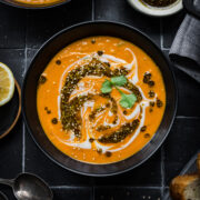 Overhead view of spicy carrot and lentil soup in black bowl on black tile.