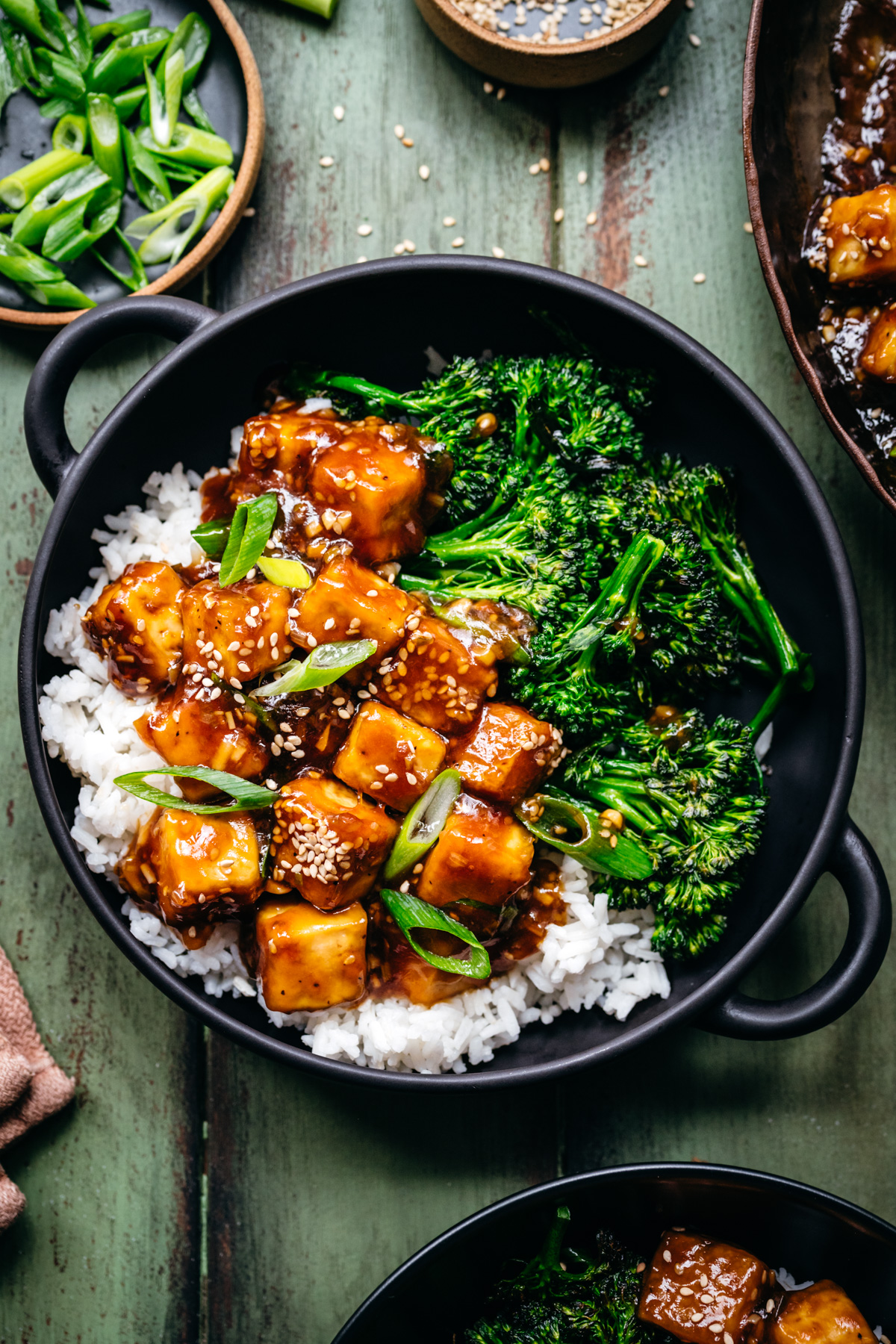 Overhead view of tofu teriyaki in a bowl over rice and broccoli.