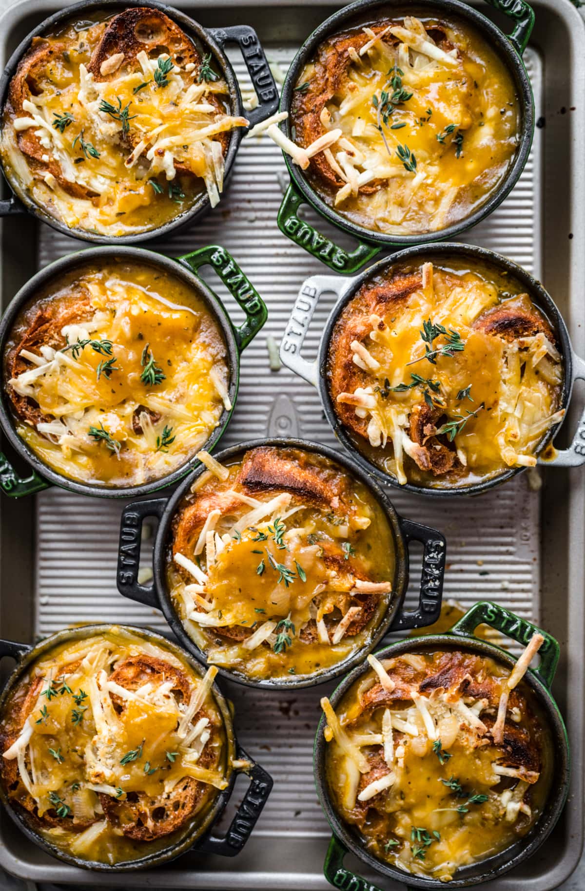 Overhead view of several cocottes filled with french onion soup with cheese melted on top.