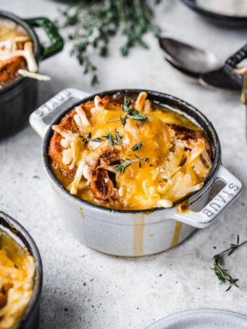 Overhead view of a crock of french onion soup with melted cheese on top.