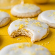 Front view of vegan lemon cookies, one with a bite taken out of it.