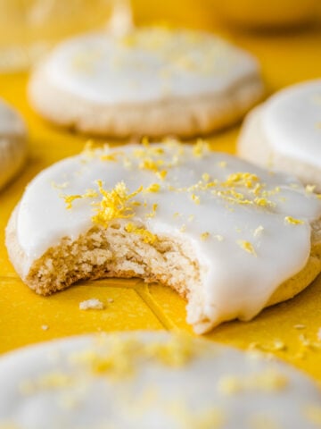 Front view of vegan lemon cookies, one with a bite taken out of it.