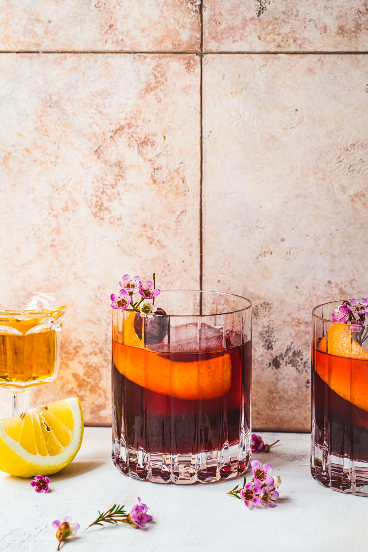 Front view of cherry old fashioned cocktail in front of a tile background.
