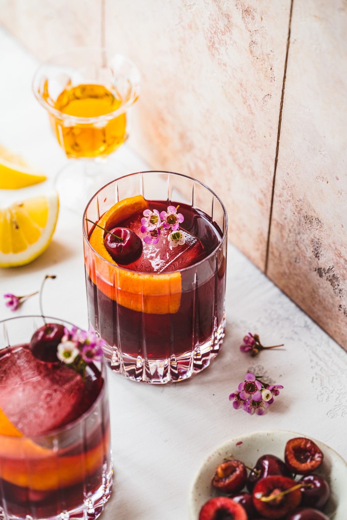 Overhead view of cherry old fashioned in front of a tile background. 