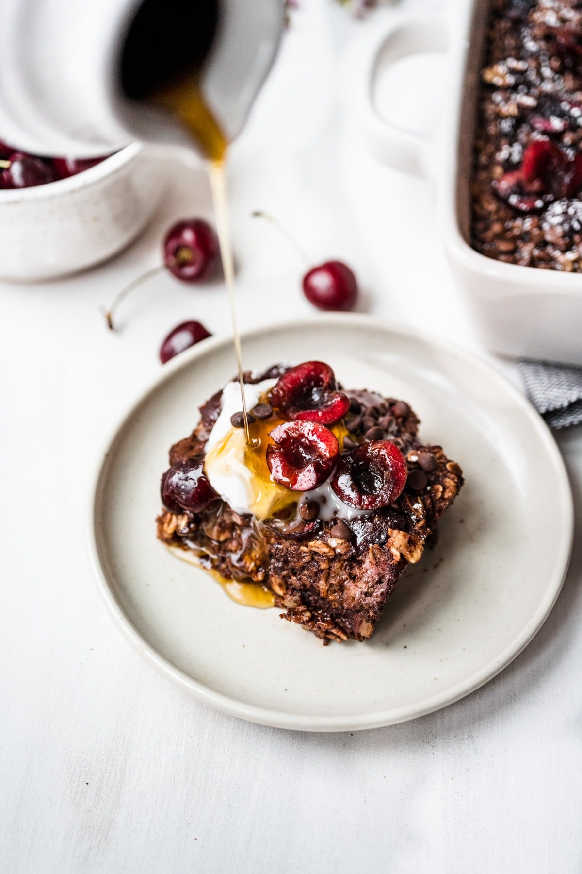 Overhead view of chocolate cherry baked oats on a plate with honey drizzled on top.