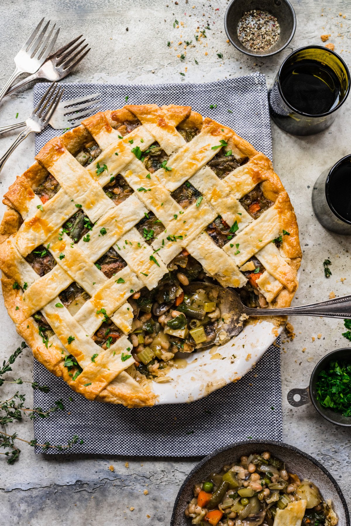 Overhead view of finished pot pie alongside glasses of wine.