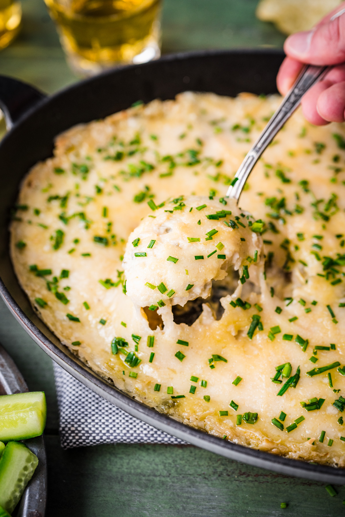 Spoonful of jalapeño artichoke dip being spooned out of a pan.