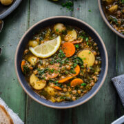 Overhead view of a bowl of potato lentil soup garnished with a lemon wedge.